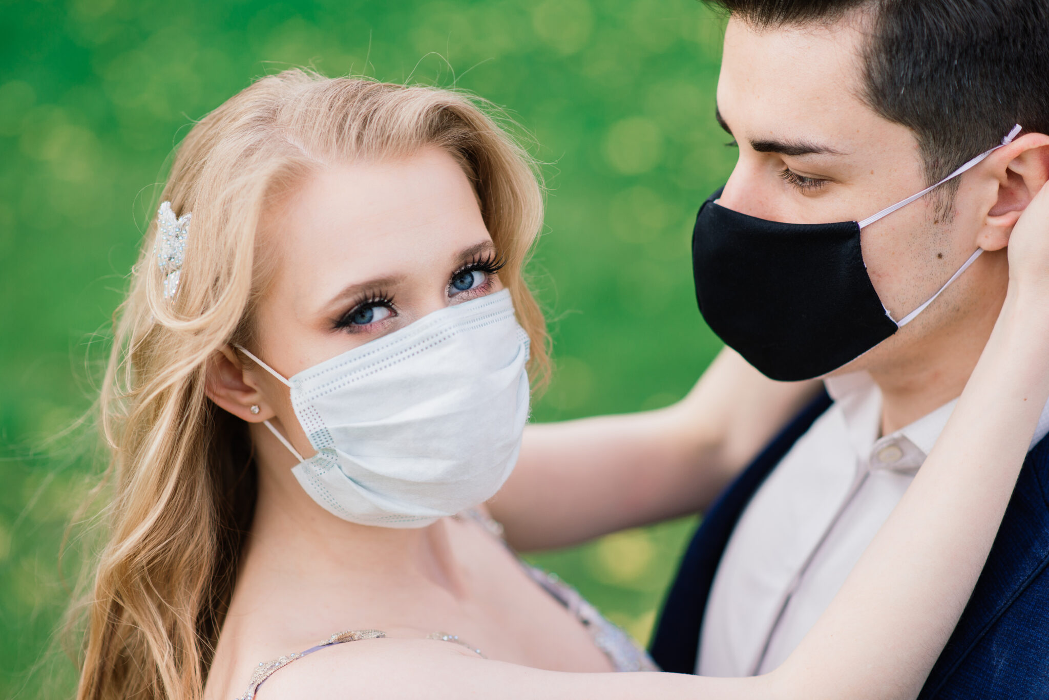 Young loving couple walking in medical masks in the park during quarantine on their wedding day. Coronavirus, disease, protection, sick